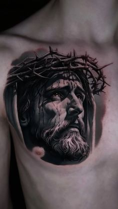 a man's chest with a tattoo of jesus and crown of thorns on it