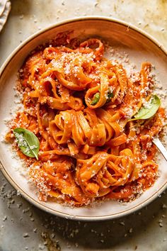 a bowl filled with pasta covered in sauce and parmesan cheese