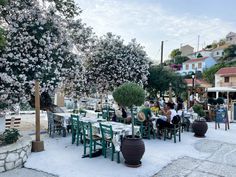 an outdoor dining area with tables and chairs covered in snow, surrounded by flowering trees