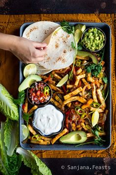 a tray filled with tacos, fries and guacamole