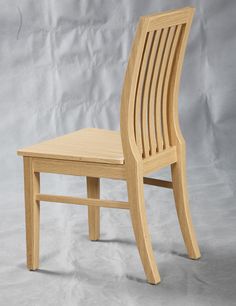 a wooden chair sitting on top of a white floor next to a gray wall in front of a grey backdrop