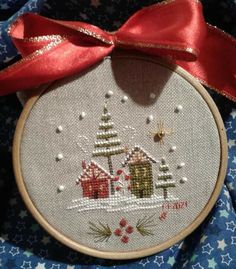 a cross stitch christmas ornament with a red ribbon