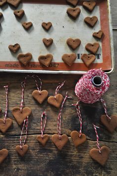 gingerbread hearts and twine spools are arranged on a baking sheet with baker's tape