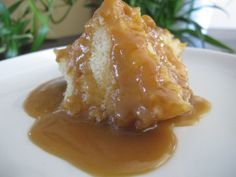 a piece of cake covered in caramel sauce on a white plate with green leaves