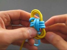 two hands are working on an ornament made out of rubber and plastic beads