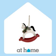 a christmas ornament with a rocking horse on it's back and the words at home above it