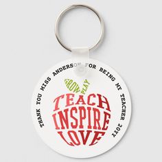 an apple shaped keychain with the words teach inspire love written in red on it