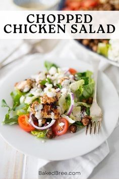 a white plate topped with chicken salad next to a bowl of salad and a fork