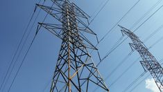 two electric towers against a blue sky with clouds