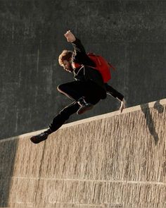 a man riding a skateboard up the side of a wall with his hands in the air