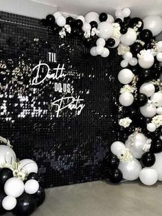 black and white balloons in the shape of flowers are hanging from a wall with sequins