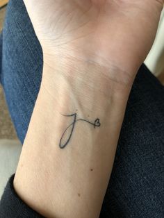 a woman's wrist tattoo with the letter j on it