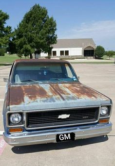 an old rusty car parked in a parking lot with the license plate on it's front