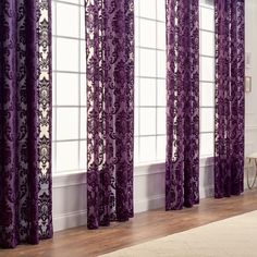 purple curtains in front of windows with white walls and wood flooring on the side