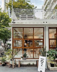 an outdoor cafe with lots of plants and potted plants on the side of it