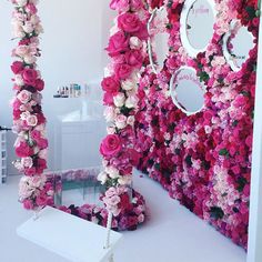 pink and white flowers are arranged on the side of a floral wall with mirrors above it