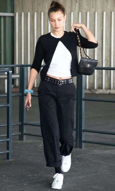 a woman in black and white is walking down the street with a handbag on her shoulder