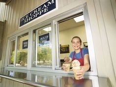 a woman holding an ice cream cone in front of a store window with the words ice cream shoppe on it