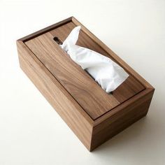 a tissue dispenser in a wooden box on a white surface with paper