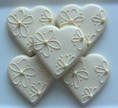 four white heart shaped cookies with bows on them