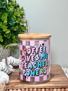 a coffee mug sitting on top of a wooden table next to a potted plant