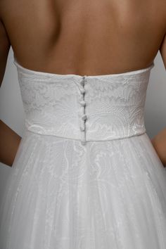 the back of a woman's wedding dress, with buttons on the waistline