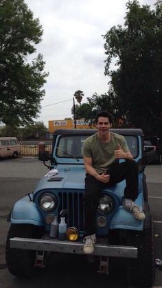 a man sitting on the hood of a blue jeep