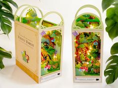 two small bags are decorated with fairy forest scenes and lights on the inside, along with green leaves