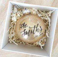 a personalized ornament in a box with white shredded paper on the floor