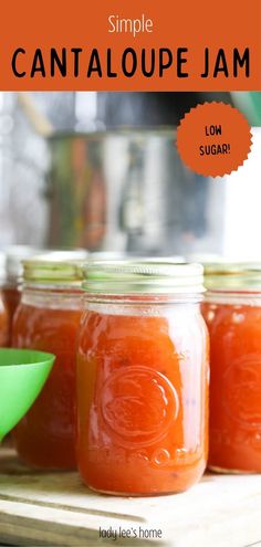 three jars filled with tomato jam sitting on top of a wooden table next to a green spoon