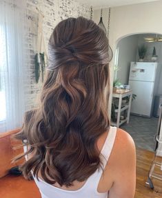 the back of a woman's head with long wavy hair in a half updo