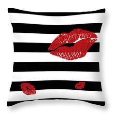 a black and white striped pillow with red lipstick on the lips in front of it