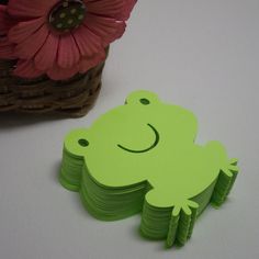 a stack of green frog coasters next to a flower