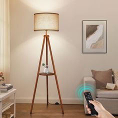 a person is holding a remote control in front of a lamp on a tripod