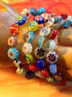 a close up of a person's hand with bracelets on it and an orange background