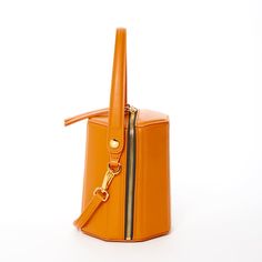 The cute Harper unexpected geometric shape gives this orange leather crossbody bag a playful but sophisticated runway savvy look. With its gold hardware, its small handle allows this orange leather bucket bag to swivel and be held in hand as a bucket. Its top zipper will keep your contents secure inside, while the cotton lined interior with 3 compartments keeps everything organized. This trendy designer crossover barrel bucket purse comes with a long and comfortable leather strap that can be flu Orange Leather Shoulder Bag With Zipper Closure, Orange Bucket Bag With Removable Pouch For Shopping, Modern Bucket Bag With Zipper Closure, Orange Crossbody Bucket Bag, Orange Shoulder Bag With Detachable Handle For Office, Orange Office Shoulder Bag With Detachable Handle, Orange Bucket Bag With Adjustable Strap, Orange Crossbody Box Bag With Detachable Strap, Luxury Bucket Bag With Zipper Closure