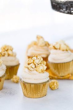 several cupcakes with white frosting and gold sprinkles on top