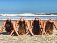 four beautiful women laying on the beach with their backs turned to one another and looking up at the sky