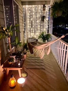 a hammock hanging from the side of a porch next to potted plants