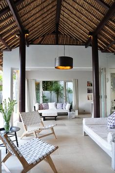 an open living room with white couches and wooden ceiling beams in front of windows