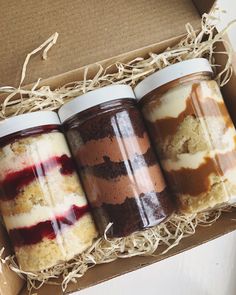 three jars filled with different types of desserts sitting in a box next to each other