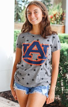 You'll be the "star" of the tailgate in our Auburn Superstar tee! This unique tee features the Auburn logo with a background of black stars on a grey tee. It's the perfect top to wear on gameday or just walking around campus! Pair it with ripped jeans or denim shorts, and your favorite pair of sneakers for a perfect look! Details: *OFFICIALLY LICENSED* Crew Neckline Short Sleeve Relaxed Fit Color: Heather Grey with Black Stars Fabrication: 50% polyester, 38% Cotton, 12% Rayon Anabella is wearing Auburn Logo, Black Stars, Sarasota Florida, Auburn Tigers, Grey Tee, Trendy Clothes For Women, Southern Style, Black Star, Sarasota