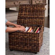 a wicker storage box with books in it on top of a carpeted floor