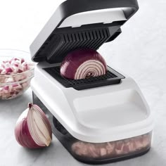 an onion slicer sitting on top of a counter next to some onions and garlic