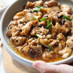 a person holding a bowl of food with meat and vegetables