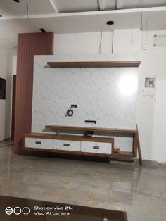 an empty living room with white walls and wooden furniture on the floor, in front of a flat screen tv