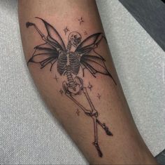 a person with a skeleton tattoo on their leg holding a cross and arrow in the other hand