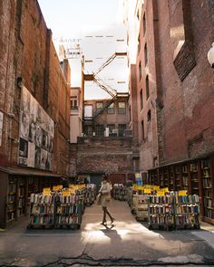 an alleyway with bookshelves and people walking through it