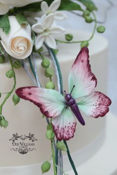 a close up of a cake with flowers on it and a butterfly sitting on top