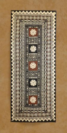 a black and white rug hanging on the wall next to a brown wall with a vase in it